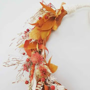 A close up of a dried flower wreath with orange flowers