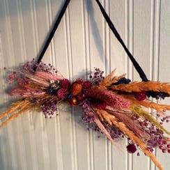 A triangular shaped display of orange and red dried flowers