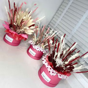 three bright pink hat boxes containing dried flowers