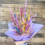 a bunch of brightly coloured dried flowers wrapped in mauve tissue paper